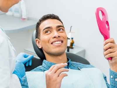 Patient smiling while holding small mirror