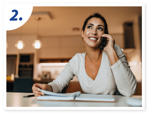 A woman in a cozy kitchen smiles while talking on the phone.