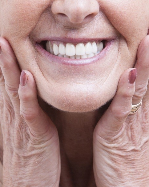 Close up of smiling senior woman touching her face