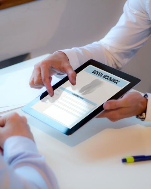 Two people looking at dental insurance form on tablet screen