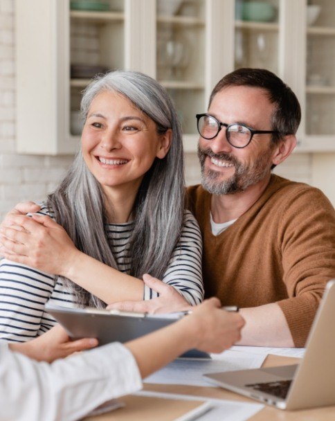 Man and woman talking to dental team member about savings plan