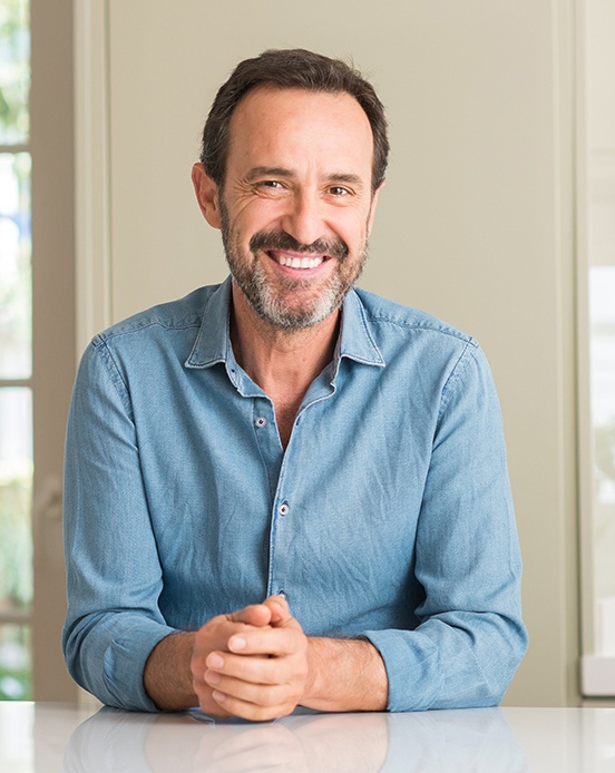 Senior man sitting at counter and smiling
