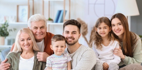 Two children with their parents and grandparents on living room couch