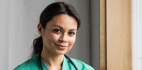Smiling woman with stethoscope and light green scrubs