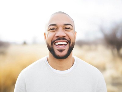 Man in white shirt smiling outside