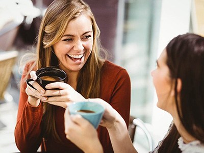 Two friends smiling while drinking coffee