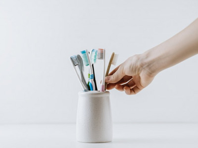 Hand reaches for toothbrush in holder