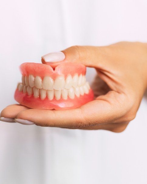 Dentist holding set of full dentures in their hands