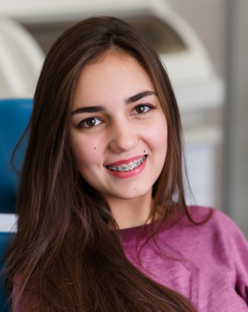 Teenage girl with braces sitting in dental chair