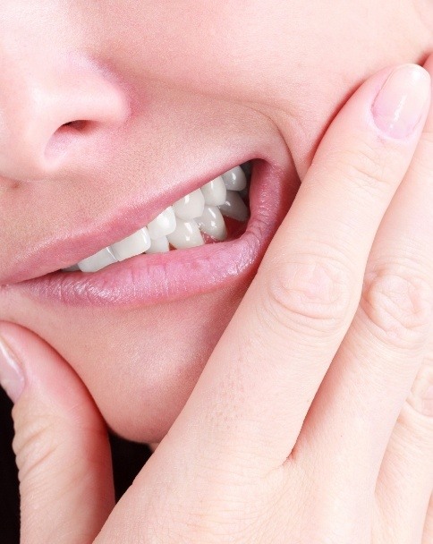 Close up of person holding the side of their jaw in pain