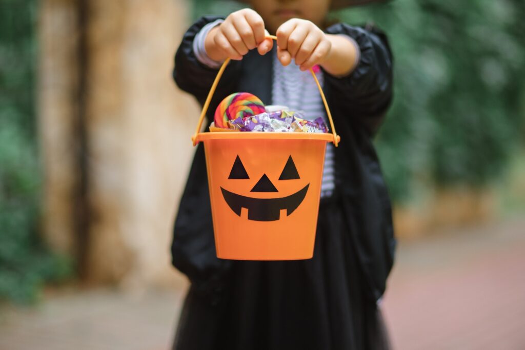 Child holding up Halloween bucket filled with candy
