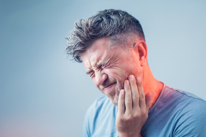 person with a dental emergency holding cheek