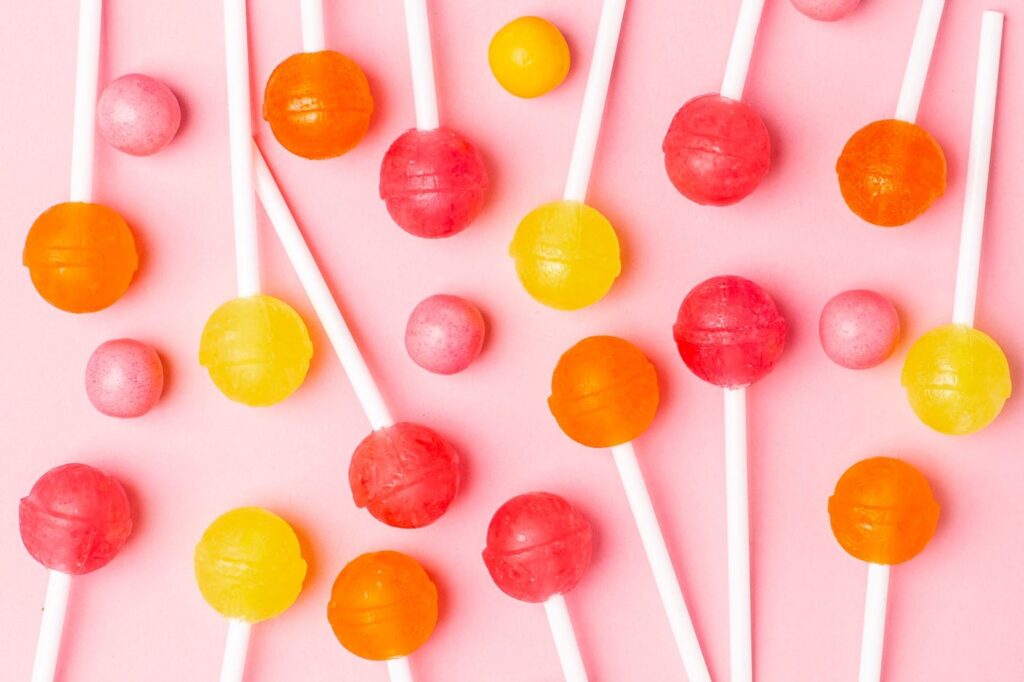 Assortment of lollipops and candy on pink surface