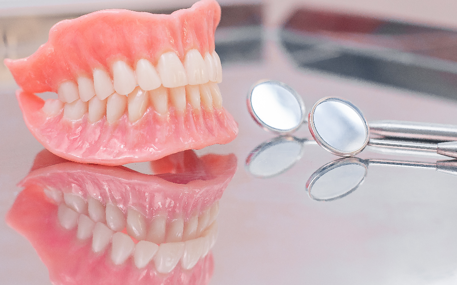Dentures on table with small dental mirror
