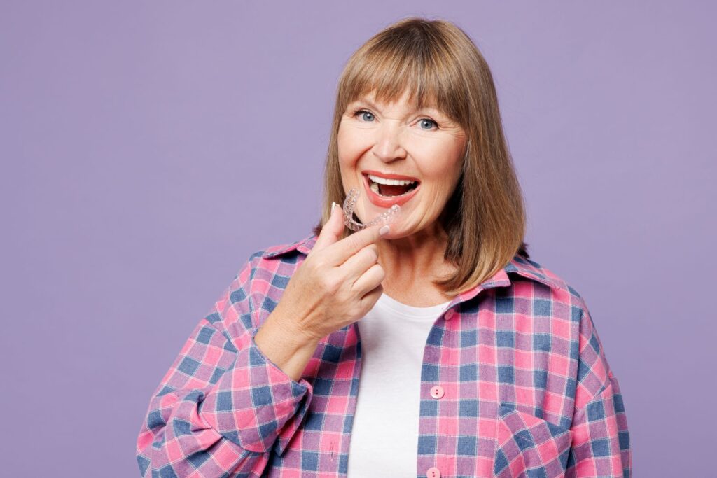 A woman holding an Invisalign aligner